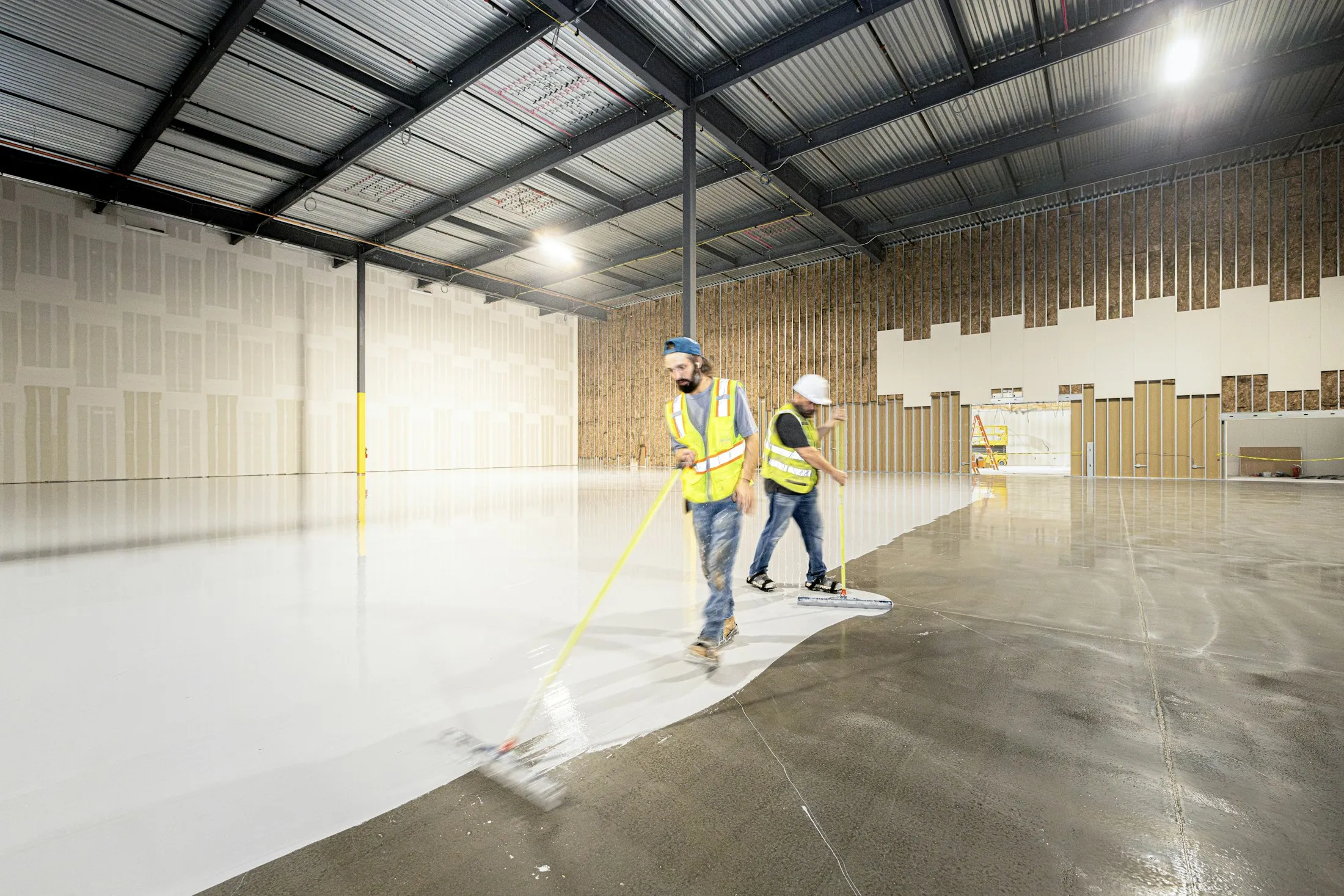 Applicators rolling a fresh resin coat across a large concrete floor